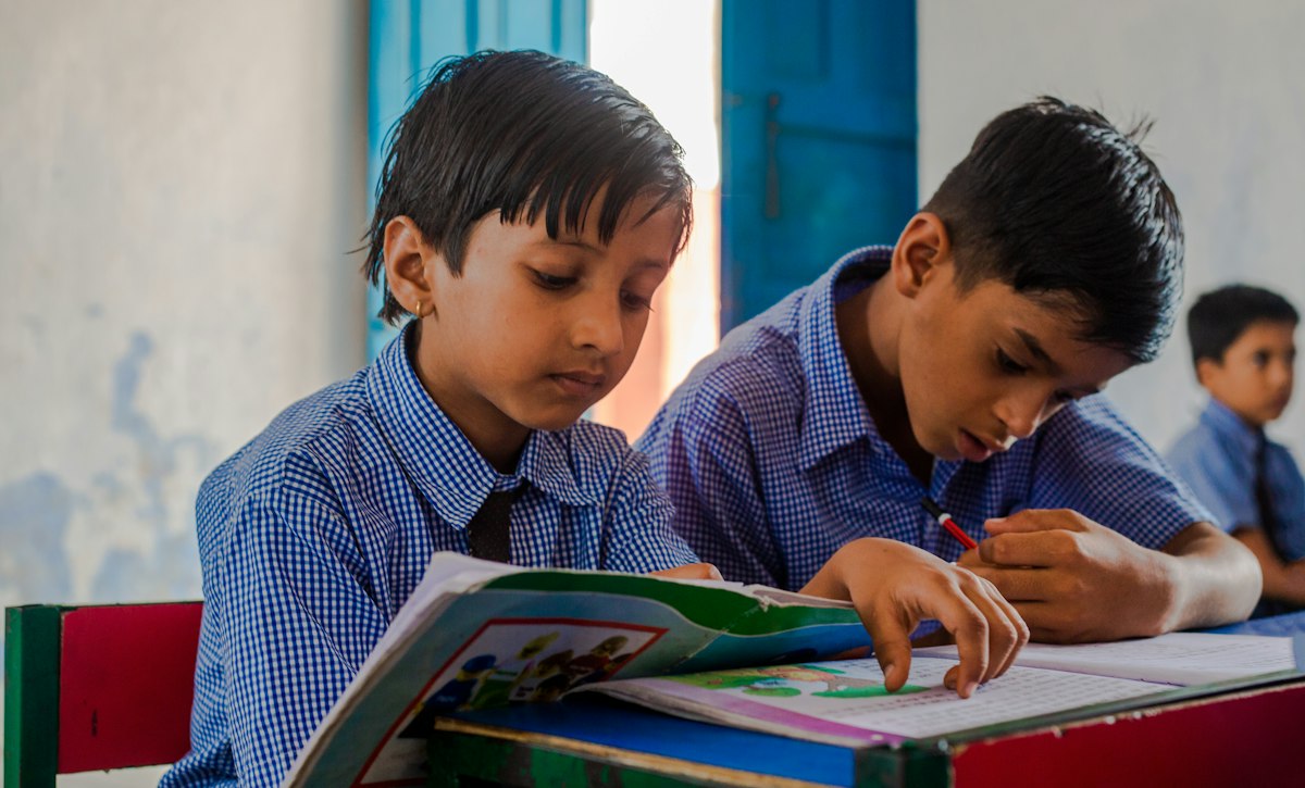 Two school boys reading a book